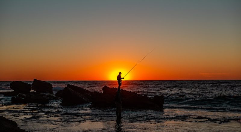 silhouette of man holding fishing rod