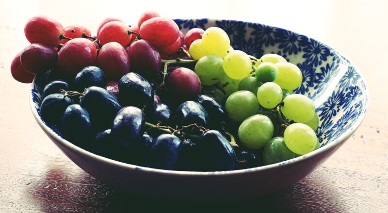 Red, Black, and Green Grapes in Round Blue and White Floral Ceramic Bowl